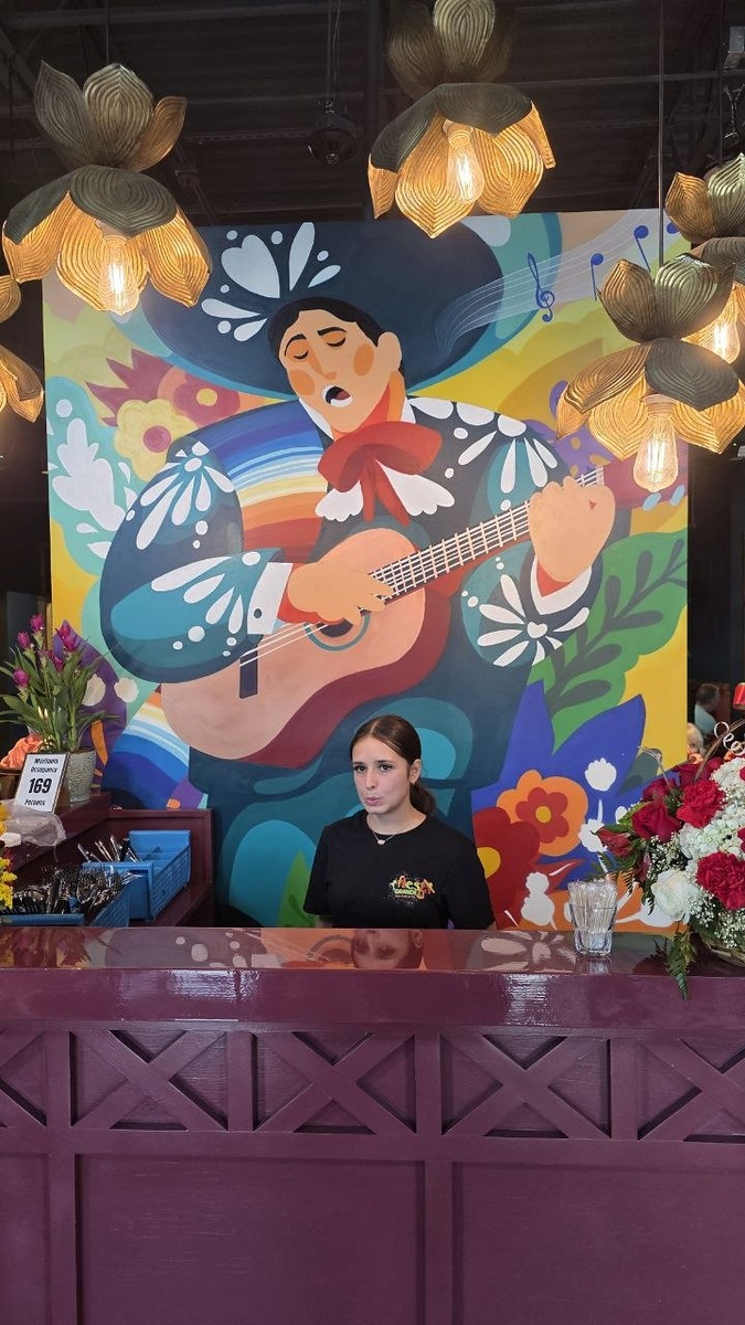 Fiesta Grande’s front desk beneath a colorful mariachi mural and decorative pendant lights in Middleton.